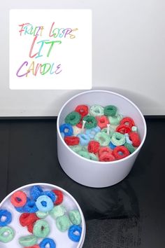 two white bowls filled with different colored doughnuts on top of a table next to a sign