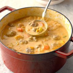 a red pot filled with soup and a ladle