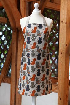 an apron on a mannequin in front of a wooden structure with a cat pattern