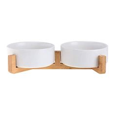 two white bowls sitting on top of a wooden stand