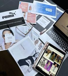 an open laptop computer sitting on top of a table next to magazines and other items