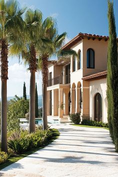 a large house with palm trees in front of it and a swimming pool on the other side