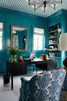 a living room with blue walls and furniture in the center, along with a chandelier