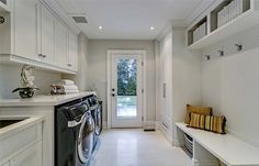 a washer and dryer in a white laundry room next to a door with open shelving