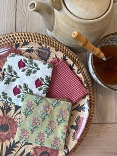 a plate with four napkins on it next to a teapot and cup filled with tea