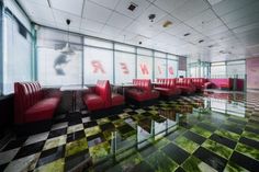 a room with checkered floor and red chairs in it's center area,