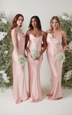 three bridesmaids in pink gowns standing next to each other and holding bouquets