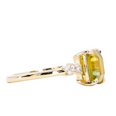 a yellow diamond ring with two diamonds on it's sides and the center stone in gold