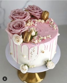 a cake with pink frosting and flowers on top is sitting on a gold plate