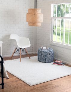 a living room with white walls and wooden flooring, a blue poufce ottoman, and a round footstool