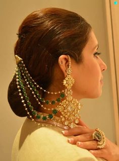 a woman wearing an elaborate necklace and earring with green beads on her left side