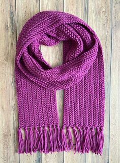 a purple knitted scarf on top of a wooden floor