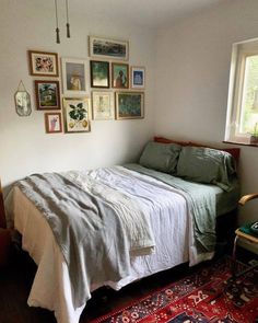 a bed sitting in a bedroom next to a window with lots of pictures on the wall