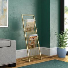 a living room with green walls and a gold magazine rack