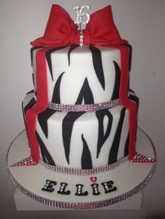 a three tiered cake decorated with black and white zebra print, red ribbon and bling