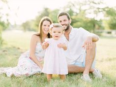 a man, woman and baby are sitting in the grass