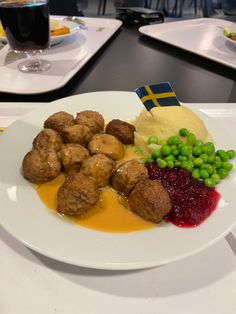 a white plate topped with meatballs, mashed potatoes and green peas