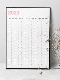 a calendar with the date on it next to some dried flowers in front of a gray wall