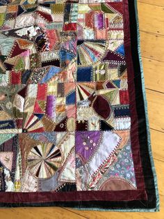 an old quilt is laying on top of a wooden floor and has been stitched together