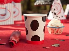 a red table topped with cupcakes and paper cups