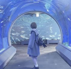 a woman standing in front of an aquarium looking at fish