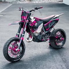 a pink and black dirt bike parked in a parking lot