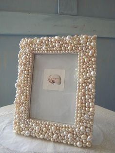 a white frame with pearls on it sitting on top of a cloth covered tablecloth