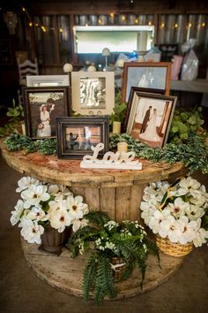 a table topped with pictures and flowers on top of a wooden table covered in greenery