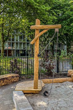 a wooden cross sitting in the middle of a park with chains hanging from it's sides