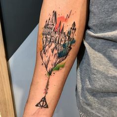 a harry potter tattoo with hogwarts castle on the back of his left arm