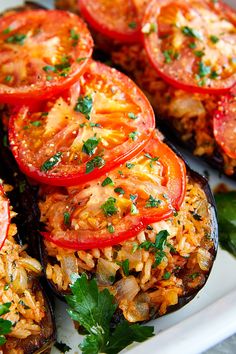 stuffed eggplant with tomatoes, rice and parsley on a white platter