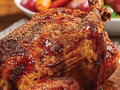 a close up of a cooked chicken on a cutting board with vegetables in the background