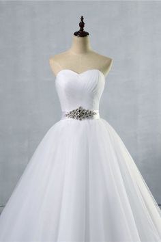 a white ball gown on a mannequin dummy with a belt around the waist