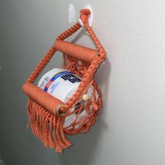 an orange basket hanging on the side of a wall with a medicine bottle in it