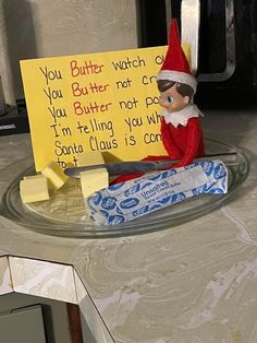 an elf is sitting on the counter next to a sign that says you butter watch or you butter not pop i'm telling you why santa claus is coming