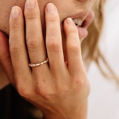 a close up of a person with a ring on their finger and her hand near her face