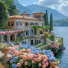 a large house with many windows and flowers in front of it on the water's edge