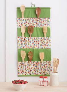 wooden utensils are hanging on the wall next to a bowl of strawberries