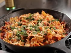 a skillet filled with pasta and sauce on top of a stove