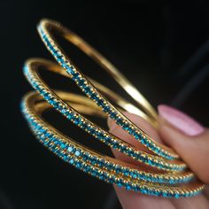 "* Handcrafted Gold Plated 4 Bangle Set. Sold as a set. * Bangles with high quality blue stones. * High Quality 22K Gold Plated. Bangles Sizes : 2.4 ( 2.20\" diameter of the inner circle) ; 2.6 ( 2.40\" diameter of the inner circle); 2.8 (2.50\" diameter of the inner circle) The gorgeous gold-plated bangles set best exemplifies the careful craftsmanship done on it -- specially picked for you by Nemali Jewelry. It has a special tone of elegance attached to it. The intricate handmade design of the Turquoise Bangle Bracelets For Wedding, Blue Round Beaded Bracelets For Wedding, Blue Bangle Bracelets For Wedding, Turquoise Bangle Bracelet For Weddings, Blue Bangle Bracelet For Wedding, Blue Festive Bracelet Jewelry, Festive Blue Bracelet Jewelry, Blue Festive Bangle Jewelry, Festive Blue Bracelet