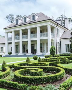 a large white house surrounded by hedges and trees