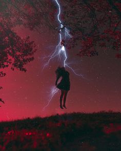 a person standing under a tree with lightning in the background