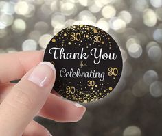 a hand holding a black and gold 30th birthday sticker that says, thank you for celebrating 30 years