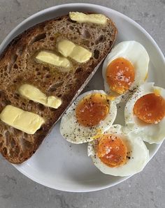 an egg and bread on a plate with buttered eggs in the middle, along with two slices of toast