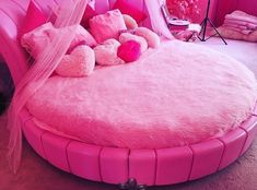 a pink bed with lots of stuffed animals on it's head and pillows in the middle