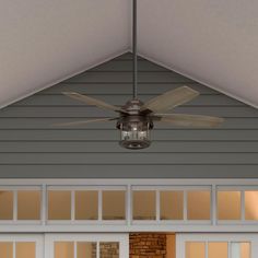 a ceiling fan mounted to the side of a house's roof above a garage door