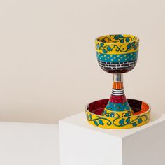 a colorful cup sitting on top of a white pedestal