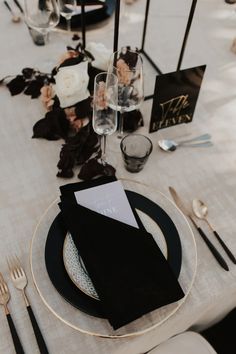 the table is set with black and white plates, silverware, and napkins