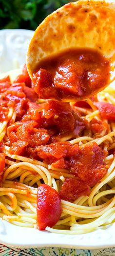 a spoonful of spaghetti with sauce and meat on it is being lifted from a white plate