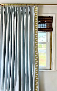 a window with a blue curtain hanging from it's side in front of a white wall